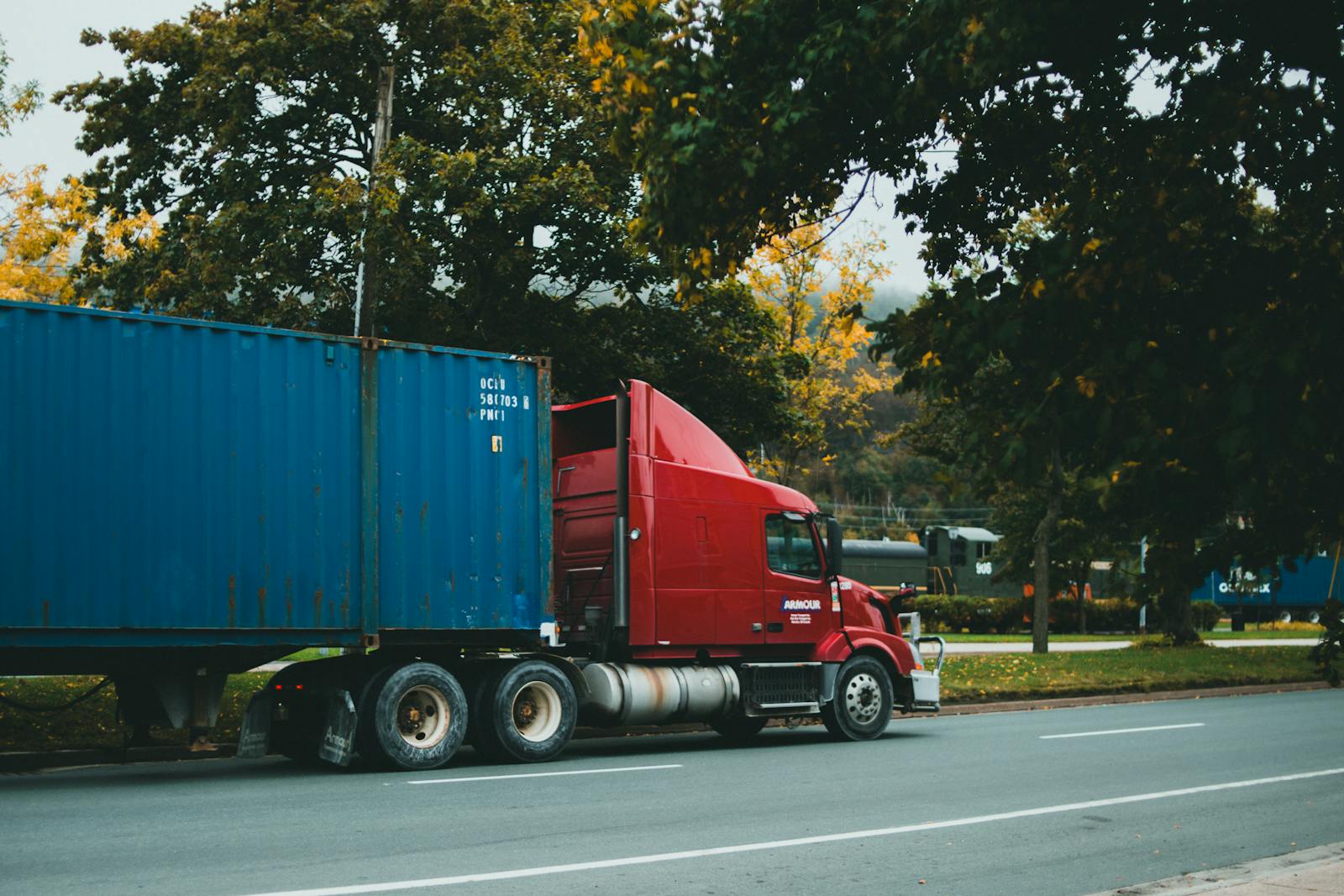 Red truck carrying a blue cargo container on the road